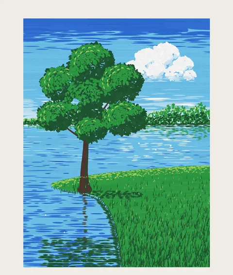 A tree on a grassy bank by a blue lake